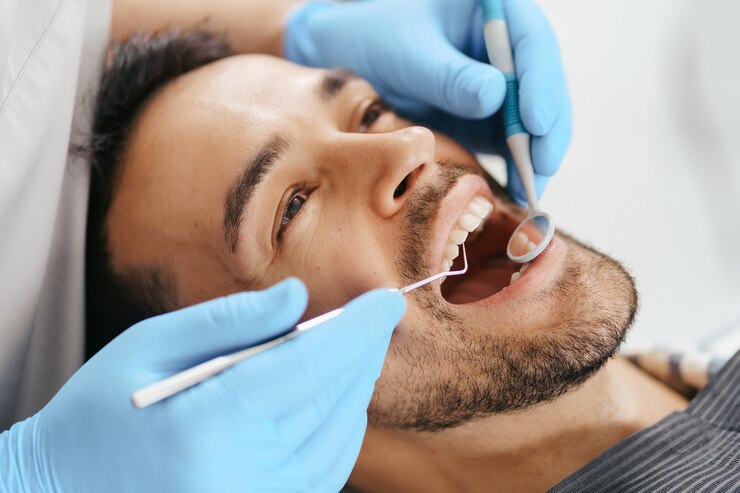 smiling young man sitting dentist chair while doctor examining his teeth 158595 7733