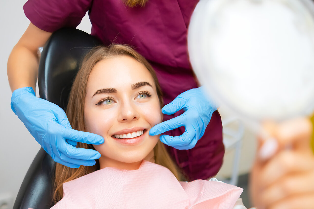 Dentist demonstrates the perfect smile of the patient after implatation of dental veneers